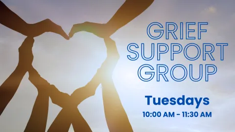 Advertisement for a Grief Support Group. 'Grief Support Group' is written in large blue letters, with 'Tuesdays 10:00 AM – 11:30 AM' below it. The background features a silhouette of hands forming the shape of a heart against a sky with the sun shining through, creating a serene and supportive atmosphere.