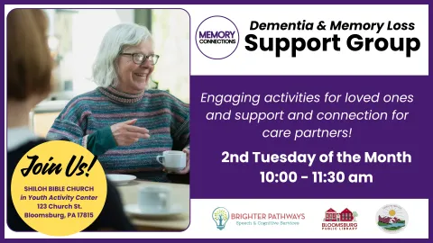 The image is an advertisement for a Dementia & Memory Loss Support Group, featuring a warm photo of an older woman smiling and talking to another person over coffee. The text provides details that the group offers engaging activities for loved ones and support for care partners, meeting on the 2nd Tuesday of the Month from 10:00 - 11:30 am at the Shiloh Bible Church in Bloomsburg, PA.